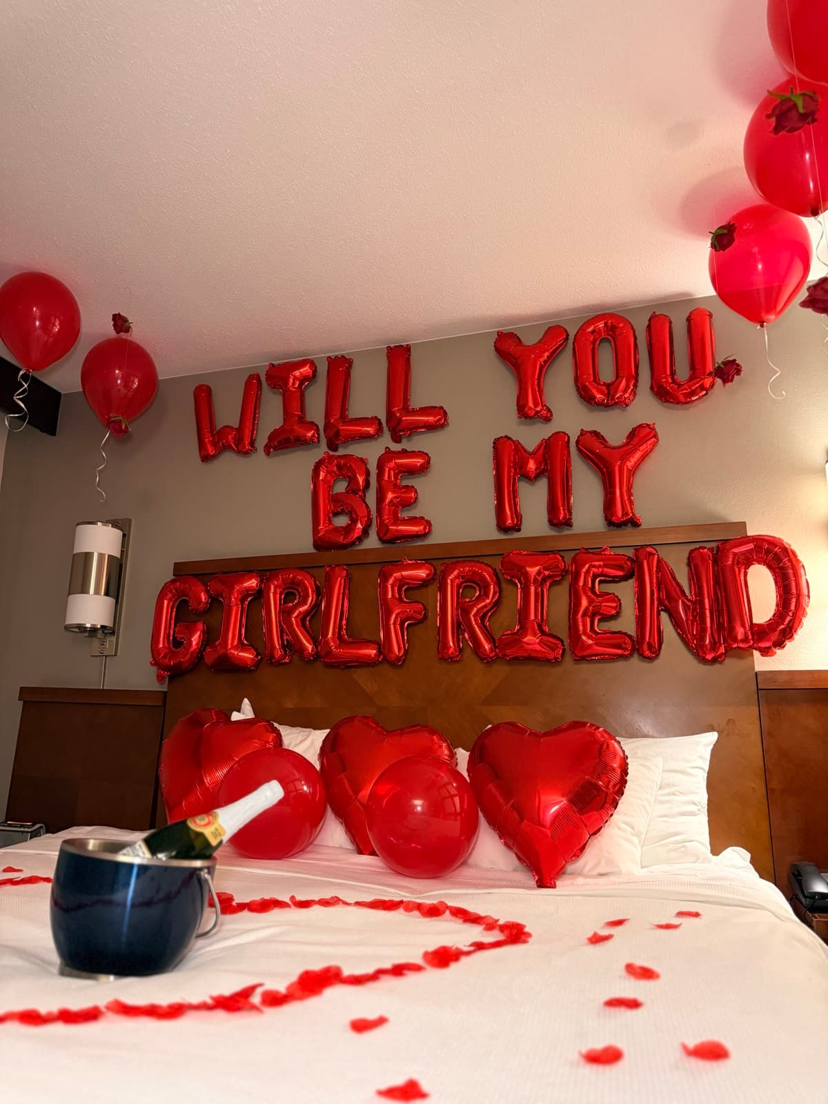 Romantic hotel room decoration with red balloons, heart balloons, and rose petals